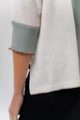 Buzo de punto confeccionado en lambswool, con diseño amplio, escote en V y mangas 3/4. Presenta una combinación de tonos rojos en la espalda con una franja central ancha y tajos laterales.