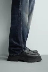 Mocasín negro de cuero liso con detalle de antifaz en el empeine y suela track gruesa y dentada.