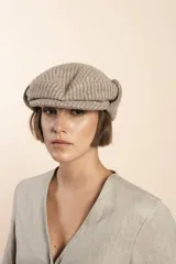 Boina de lana color beige con diseño de espiga, visera corta y orejeras plegables.