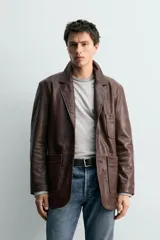 Blazer de corte relajado confeccionada en piel con acabado napado, cuello con solapas de muesca, manga larga, bolsillos frontales de plastrón y cierre frontal de botonadura.
