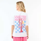 Camiseta blanca de corte oversize con cuello redondo y manga corta. Presenta un estampado pequeño en el pecho con la frase 'Lobster Market', un gráfico de una rodaja de naranja y un patrón de cuadros celestes.