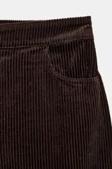 Pantalón de tiro medio confeccionado en tejido de pana, con diseño de pierna ancha, bolsillos delanteros y traseros, y cierre frontal con cremallera y botón.