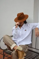 Sombrero marrón de ala ancha confeccionado en paño de lana afieltrada a mano, con cinta decorativa del mismo material alrededor de la copa.