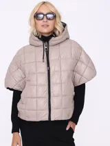 Campera corta color beige con capucha, cierre frontal con cremallera y mangas cortas. Diseño acolchado con patrón de rombos.