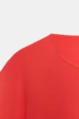 Top corto de punto color rojo coral, con cuello redondo y mangas cortas amplias con sisa ancha y costura central vertical.