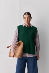 Chaleco tejido de punto color beige, con cuello redondo, terminaciones en rib y lazos laterales regulables que permiten ajustar la prenda.