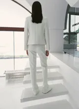 Chaqueta de diseño recto color blanco, con cuello mao, manga larga con puños abotonados, cierre frontal de botones y bolsillos de ribete delanteros.