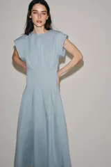 Vestido midi de Zara Woman Collection confeccionado en hilatura de algodón color celeste, con cuello redondo, manga corta y detalles de pliegues en la cintura. Presenta falda en línea evasé y cierre en la espalda con abertura y botón.