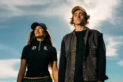 Chaleco de denim negro con efecto deslavado, diseño sin mangas, bolsillos frontales con solapa, costuras en contraste y botones metálicos.