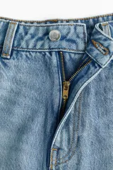 Pollera mini de cinco bolsillos confeccionada en denim de algodón rígido, con diseño acampanado, cintura estándar y cierre frontal con botón y cremallera.