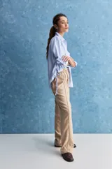 Pantalón de corte recto y holgado, color marrón, con costuras frontales verticales que estilizan la silueta.