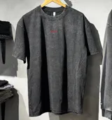 Remera oversize de algodón 100% color negro con lavado stone wash, de manga corta, cuello redondo y diseño bordado con la palabra 'Become.' en rojo en la parte superior trasera.
