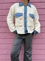 Chaqueta color crema de corderito con detalles en jean azul en cuello, solapa, bolsillos y puños.