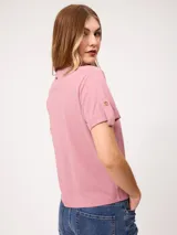 Remera blanca de manga corta con vuelta en los puños y detalle de botón dorado. Presenta cuello redondo y corte recto.