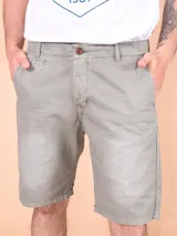 Bermuda de gabardina color gris, con cierre frontal de botón y cremallera, bolsillos laterales y pasacintos.