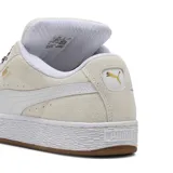 Championes Puma Suede XL Wild de mujer, en color gris claro con franja lateral blanca y suela de goma marrón. Presentan cordones anchos con estampado animal print tipo leopardo y detalles de la marca en dorado metalizado en el lateral.