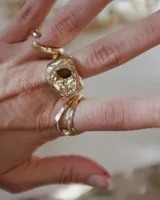 Anillo dorado con forma irregular y un agujero en el centro.