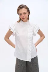 Blusa de manga corta con volados en los hombros, cuello alto con ribete fruncido y cierre frontal desplazado con botones y detalle de volado.