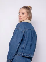 Campera de jean blanca con interior de corderito color beige, dos bolsillos grandes en la parte frontal y siete botones metálicos.