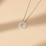 Collar de plata 925 con dije circular que presenta un diseño geométrico calado con un cuadrado en el centro.