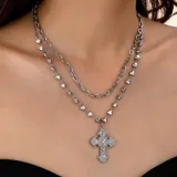 Juego de dos collares dorados, uno con cadena de eslabones y otro con cadena de bolitas con forma de corazón y dije de cruz con incrustaciones de strass.