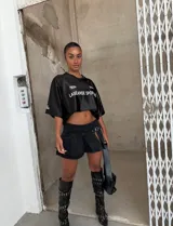 Minifalda de tiro bajo confeccionada en denim negro, con diseño plisado y detalle de hebilla frontal. Presenta un tajo lateral que aporta un estilo moderno y audaz.