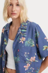 Camisa azul con estampado floral multicolor, de corte recto, manga corta y cuello camisero.