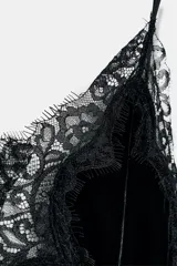 Vestido midi de terciopelo con escote en pico y tirantes finos. Presenta aplicaciones de encaje a tono y un diseño de bajo asimétrico.