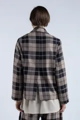 Blazer marrón con estampado a cuadros negros y blancos, de corte recto, solapa clásica, cierre cruzado con botones y bolsillos frontales.