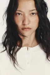 Vestido corto blanco con cuello redondo y manga larga tipo murciélago. El bajo tiene un acabado voluminoso con tejido combinado a tono y cierre frontal con botones.