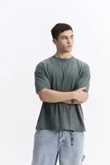 Remera de manga corta, color verde oscuro con efecto gastado o lavado, de corte holgado (boxy) y escote redondo.