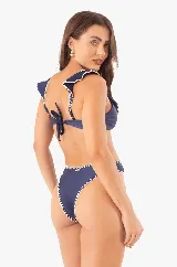 Conjunto de bikini azul marino con volados bordados a mano con hilo blanco. El top tiene copas extraíbles, tirantes ajustables y lazo en la espalda. La bombacha es tradicional con bordado a mano. El tejido se adhiere muy bien a la piel, proporcionando mayor comodidad y una compresión suave, además de un ligero brillo.