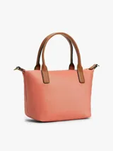 Cartera tote Tommy Hilfiger de nailon color salmón, con dos asas superiores de cuero sintético marrón y correa tejida extraíble. Cuenta con cierre de cremallera y detalle del monograma TH en metal dorado en la parte delantera.