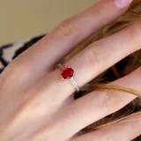 Anillo plateado de acero con un cristal rojo en forma de lágrima y pequeños cristales blancos alrededor.