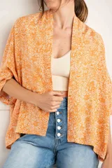 Kimono oversize color naranja con estampado floral blanco, mangas 3/4 y confeccionado en rayón.