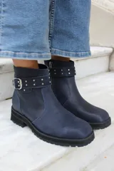 Bota corta de cuero azul con suela track negra, detalle de tira con hebilla metálica y tachas decorativas en el tobillo.