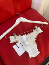 Bombacha colaless de encaje blanco suave, con cintura fruncida y detalle de volados.