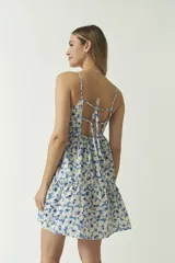 Vestido corto con estampado floral en tonos azules y blancos, breteles finos y corte escalonado.