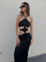 Vestido largo negro de lycra con escote halter y aberturas geométricas en la cintura.