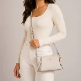 Cartera bandolera Guess modelo Devon de diseño estructurado, color gris con efecto texturizado. Presenta herrajes dorados, logo triangular frontal de la marca y charm colgante decorativo. Cuenta con cierre superior y correa ajustable.