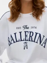 Buzo blanco oversize de manga larga con cuello redondo, ribetes en contraste en las mangas y estampa frontal con la inscripción "BALLERINA EST. The 1976".