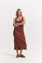 Vestido largo de morley color marrón, con escote redondo, silueta al cuerpo y aberturas laterales en el ruedo.