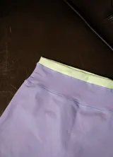 Calza corta deportiva tiro alto, color lila con pretina ancha de contraste en color verde lima.