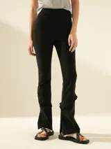 Pantalón negro elastizado de calce ajustado, con cintura elástica y cierre lateral. Presenta volados y tajos en las botamangas.