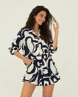 Conjunto de camisa y short de color blanco con estampado abstracto en azul marino. La camisa es de manga larga con cuello camisero y cierre frontal de botones, mientras que el short cuenta con cintura elástica fruncida y bolsillos laterales.