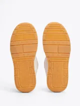 Zapatillas Tommy Jeans de corte bajo, color gris claro, confeccionadas en ante con interior de poliéster y suela de goma color caramelo. Presentan cordones blancos, logo de la marca en la lengüeta y etiqueta de Tommy Jeans en el lateral.