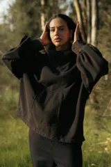 Canguro negro oversize de algodón, con capucha amplia, cuello alto integrado y ruedo ajustable con tancas.