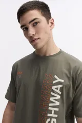 Remera de manga corta color verde militar, con escote redondo y ajuste regular. Presenta un estampado frontal con la palabra "HIGHWAY" en blanco y naranja, y un pequeño estampado en el pecho con el número "#76" y texto en naranja.