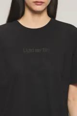 Remera negra de algodón con calce oversize, escote redondo, mangas cortas y estampa frontal con la frase "Light my fire".