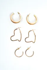 Set de tres pares de aros dorados, que incluye aros de argolla anchos, aros con forma de corazón y aros pequeños texturizados con cierre de presión.